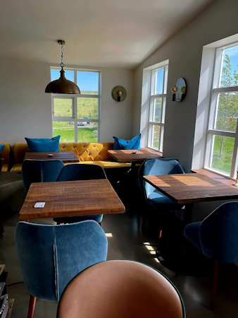 A comfortable dining area with tables, chairs, and a sofa at Hotel Godafoss in North Iceland.