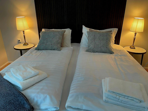 A double bed with linen, towels, and a bedside lamp at Hotel Godafoss in North Iceland.