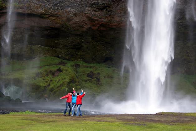 Travelers posing in front of the beautiful Seljalandsfoss waterfall in Iceland.