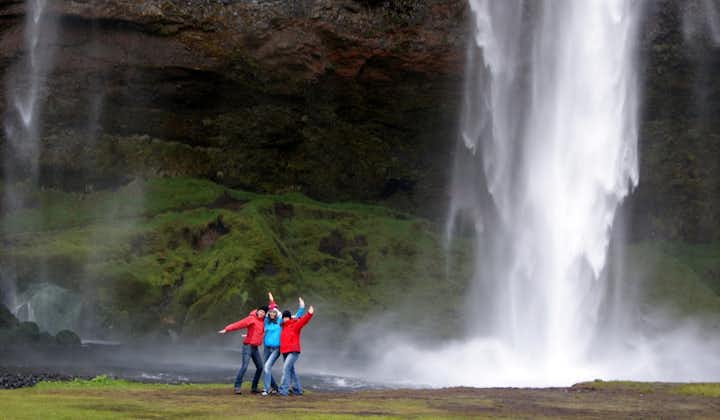 Travelers posing in front of the beautiful Seljalandsfoss waterfall in Iceland.