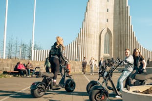 Experience the thrill of exploring Reykjavik on an e-scooter, with the majestic Hallgrimskirkja Church as your backdrop.