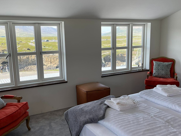 A suite with armchairs and beautiful river and waterfall views at Hotel Godafoss.