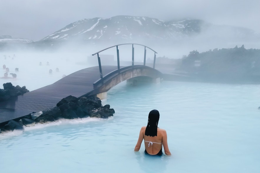 游客在冰岛蓝湖温泉的桥旁放松