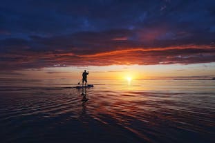 Experience the serenity of stand-up paddling as the sun sets over the majestic Atlantic Ocean.