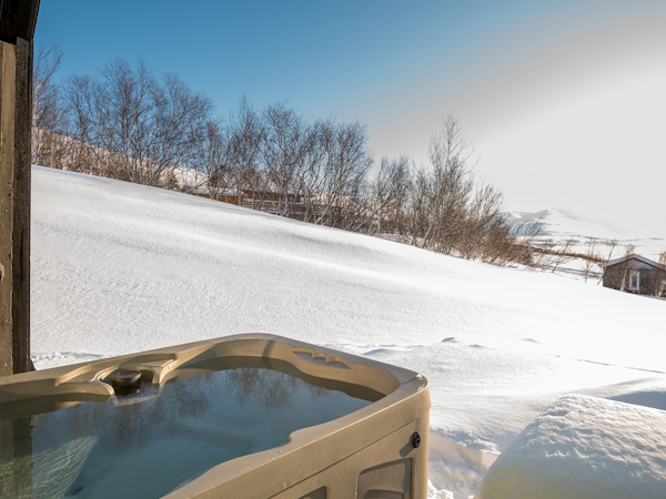 Unwind in the outdoor tub amidst the snowy splendor at Viking Cottages and Apartments.