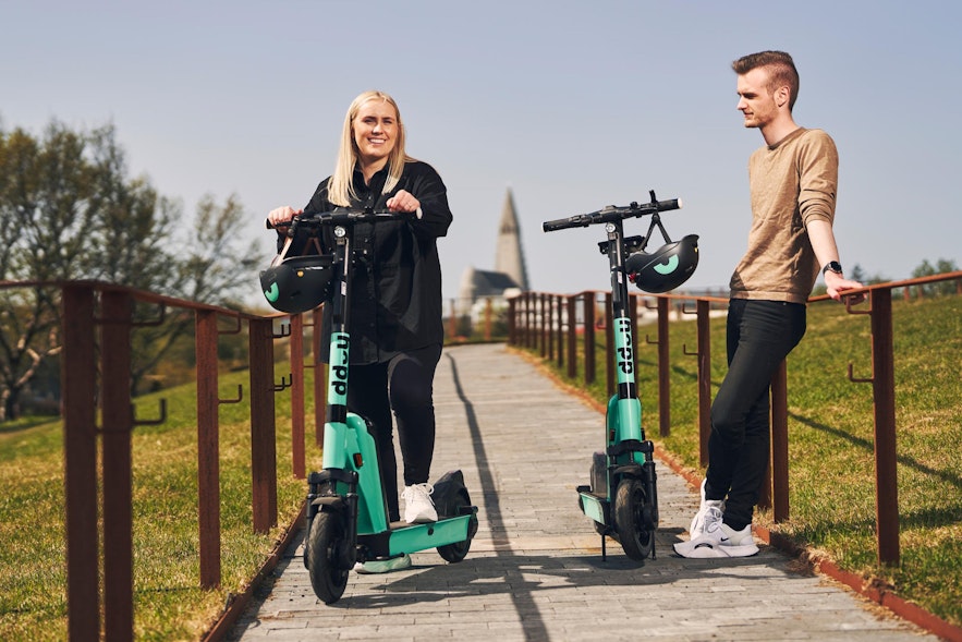 A couple using the Hopp scooters with Hallgrimskirkja in the background