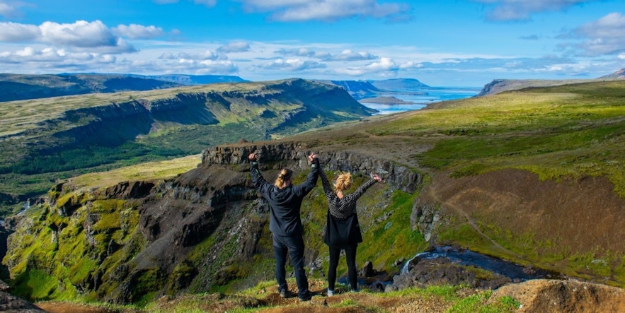 Two women on the top of Glymur waterfall in Hvalfjordur, where they could have used the AllTrails app for guidence