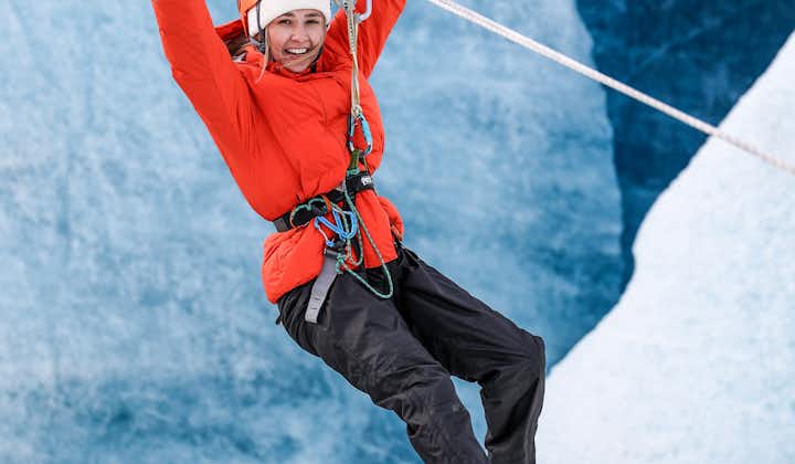A person puts their hands up as they fly down a zip line on a glacier.