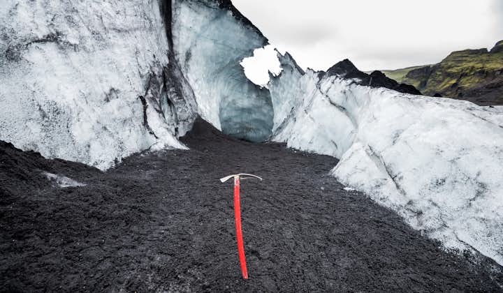An ice axe planted in the ground during a hike across the Solheimajokull glacier.