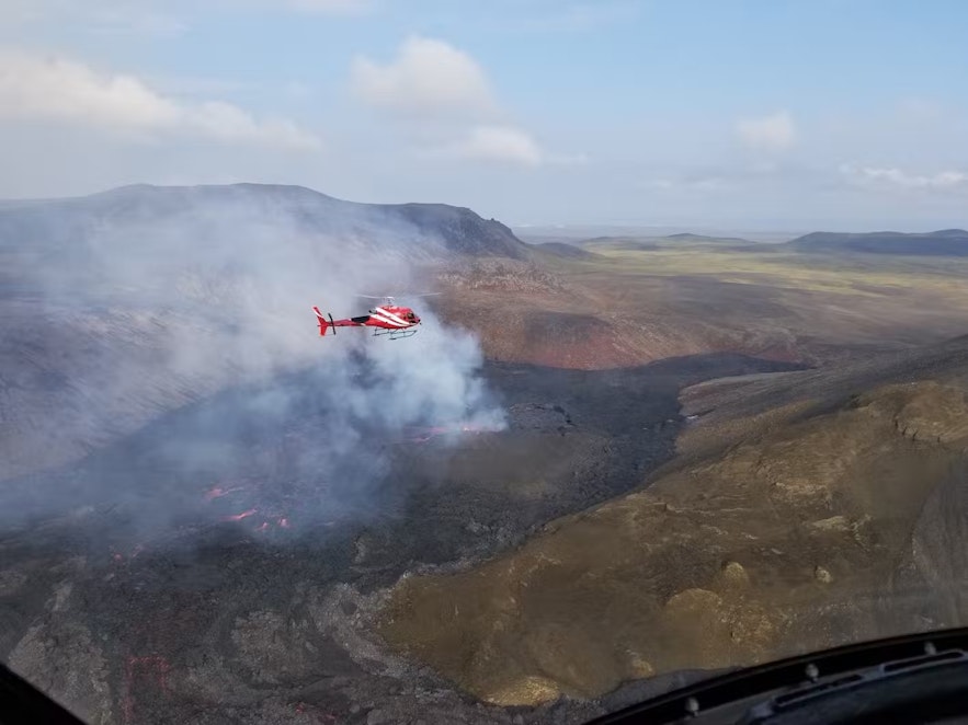 A helicopter soars over an erupting volcano in Reykjanes.