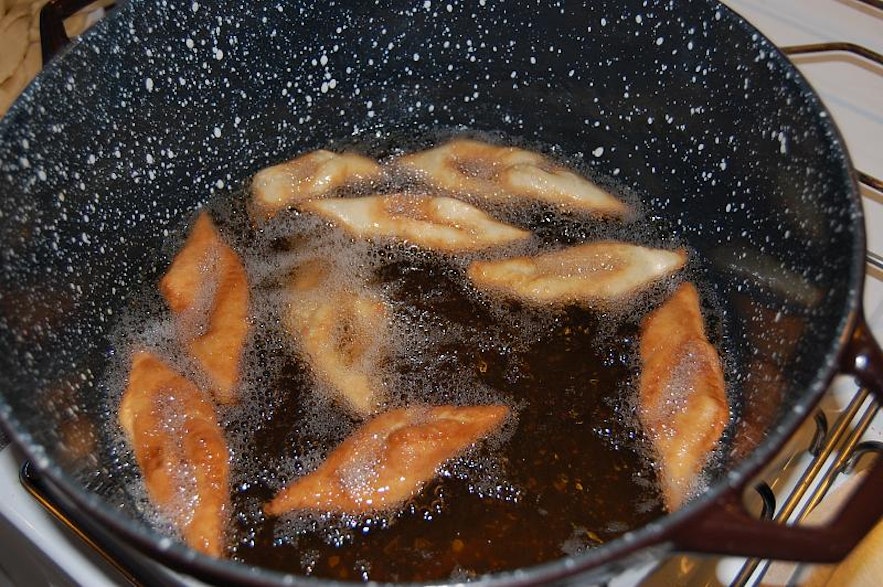 Twisted kleina dough being deep fried in a pot