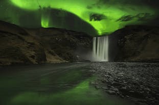 Mesmerizing northern lights gracefully dance over the majestic Skogafoss waterfall, creating a truly enchanting spectacle.