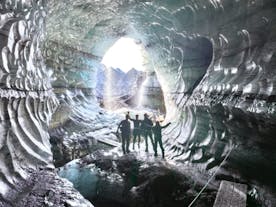 A group standing in the opening of Katla ice cave in Iceland.