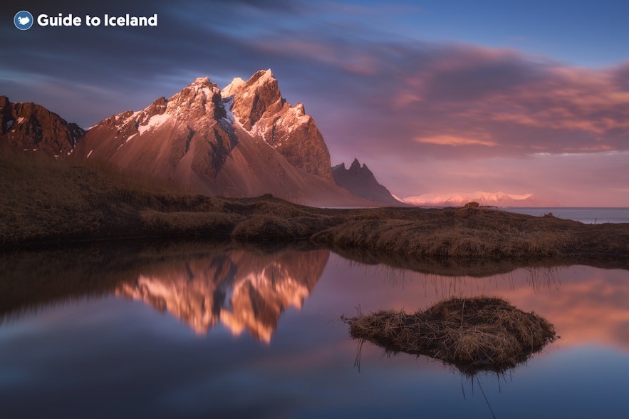 The twin peaks of the Eystrahorn mountain in Southeast Iceland, reflected in a calm body of water.