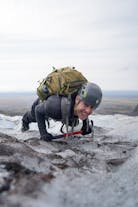 A person holding an ice axe does a push-up on a glacier in Iceland.