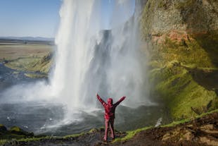 A traveler posing behind the Seljalandsfoss waterfall.