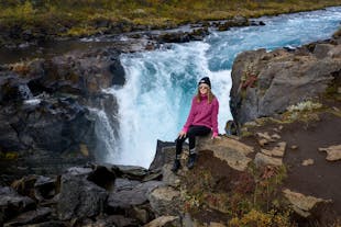 A photo of a traveler posing in front of the Bruarfoss waterfall in Iceland.