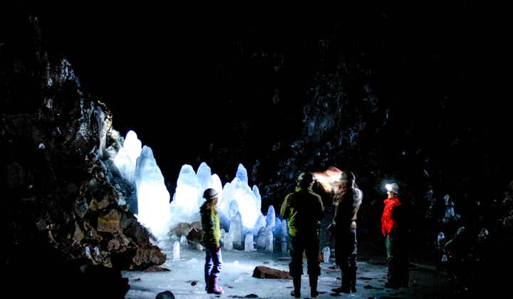 People standing, surrounded by ancient ice formations, some over 400 years old, at Lofthellir ice cave.