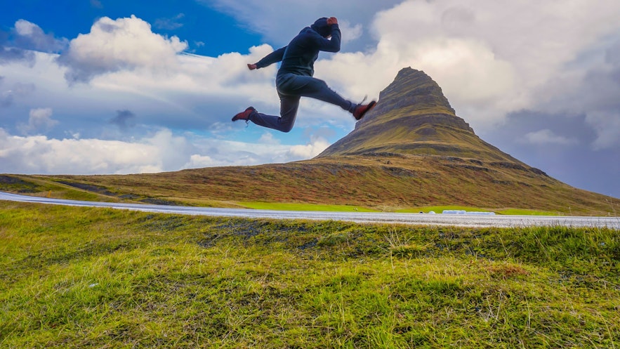 Action shot of man jumping with illusion of foot against mount kirkjufell Iceland