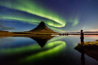 See Kirkjufell mountain with a band of northern lights in the Snaefellsnes Peninsula.