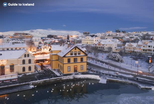 Snow covers colorful houses and the beautiful Tjornin pond in Reykjavik.