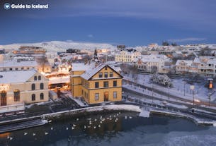 Snow covers colorful houses and the beautiful Tjornin pond in Reykjavik.