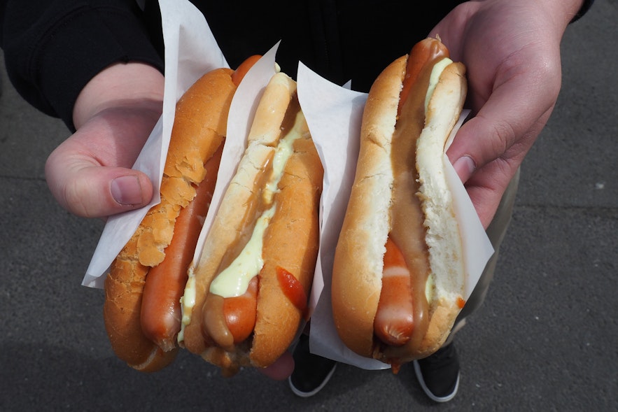 Isländische Hot Dogs "mit allem" beinhalten süßen braunen Senf, Remoulade, Ketchup, rohe und gebratene Zwiebeln