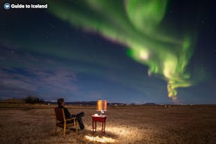 A man sat on a chair, enjoying a northern lights display in Iceland.