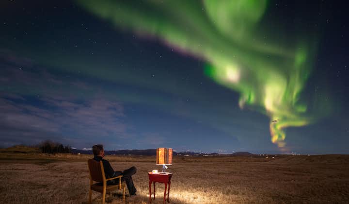 A man sat on a chair, enjoying a northern lights display in Iceland.