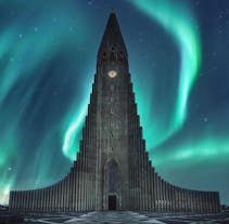 Hallgrimskirkja framed by the ethereal glow of the northern lights, blending natural wonder with architectural beauty in this captivating scene.