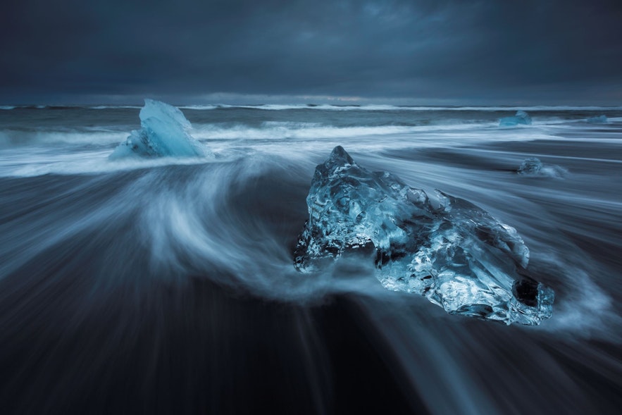 The ocean washes ice bergs back on to the black sand beach by Jokulsarlon glacier lagoon