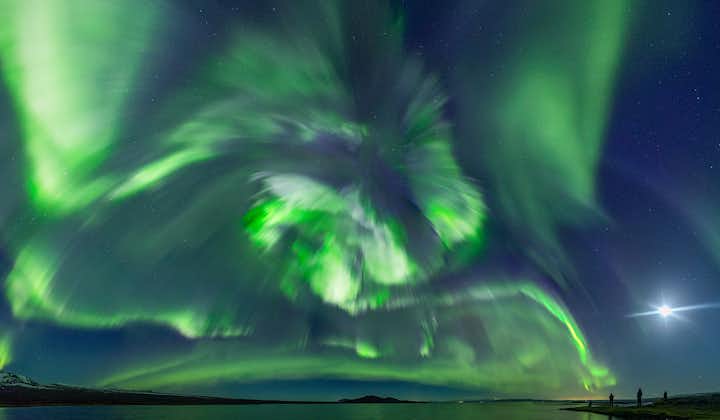 A swirl of northern lights appears on a coastal area near Reykjavik.