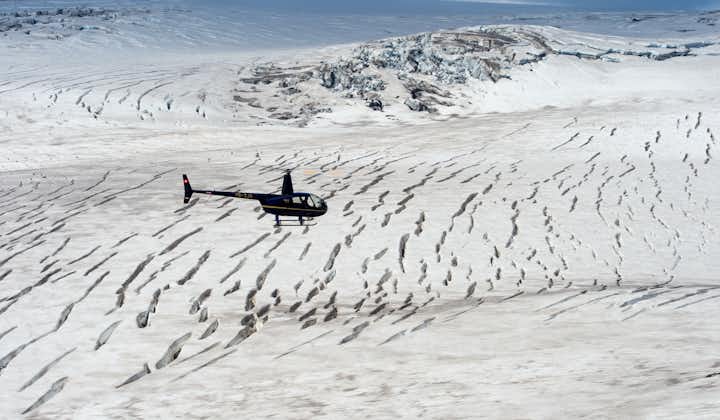 A helicopter flies over an icy glacier on a tour in Iceland.