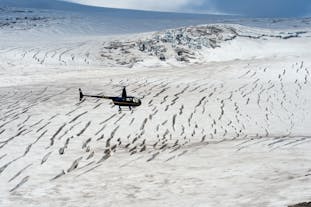 A helicopter flies over an icy glacier on a tour in Iceland.