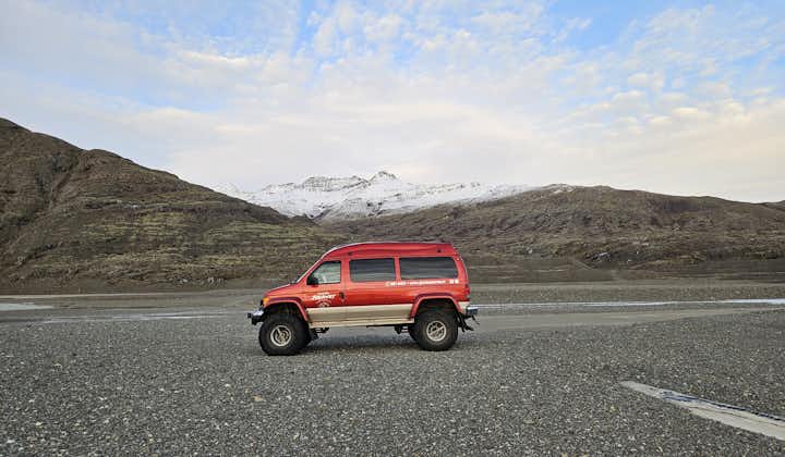 A red super jeep parked in front of snowy mountains.