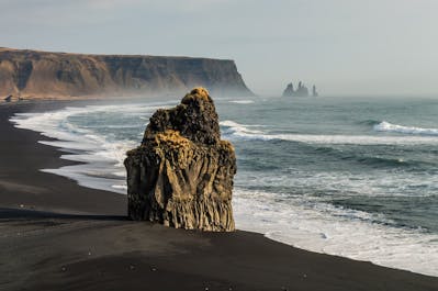 Reynisfjara's unique beauty: a coastal symphony of black sands, towering cliffs, and foamy waves.