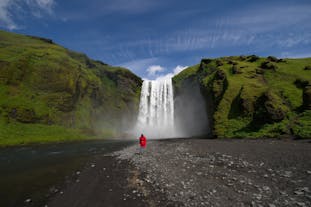 A traveler posing with the awe-inspiring beauty of the Skogafoss waterfall in the background.