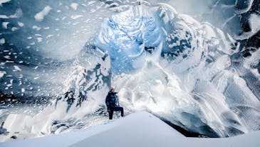 A person stands inside a beautiful ice cave.