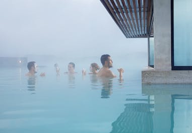 People bathing in the milky-blue waters of the Blue Lagoon geothermal spa on a trip to Iceland.
