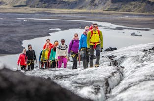 A group of people walks up the icy terrain of the Solheimajokull glacier.