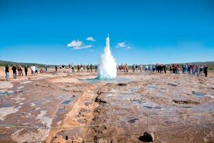 People watch as the Strokkur geyser erupts high in the air at the Geysir geothermal area in the Haukadalur valley.
