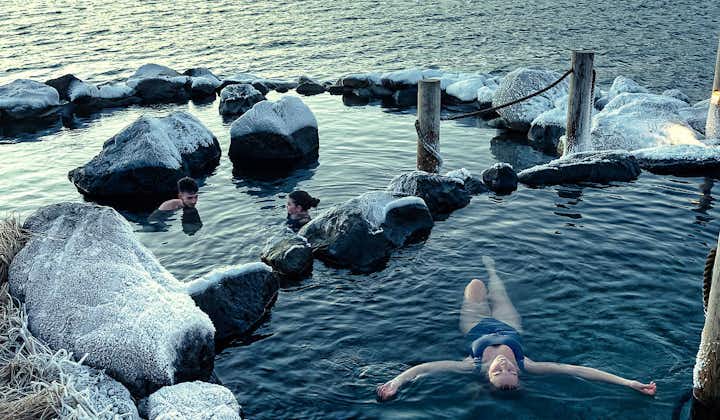 A person floats on their back, relaxing in one of the natural hot pools at the Hvammsvik Hot Springs.