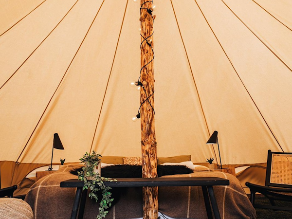 The interior of one of the Golden Circle Tents units, featuring a double bed, bedside lamps, and rugs.