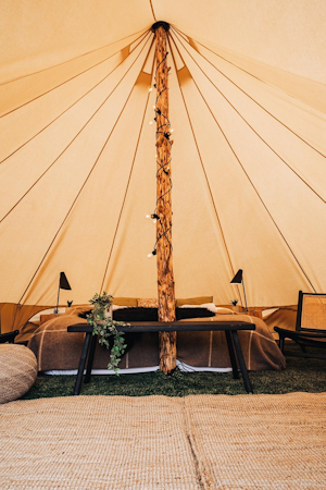 The interior of one of the Golden Circle Tents units, featuring a double bed, bedside lamps, and rugs.