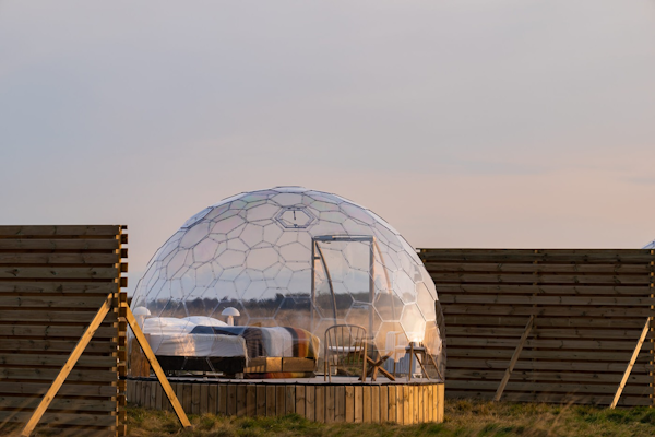An Aurora Igloo glamping pod, with two wooden fences either side for privacy.