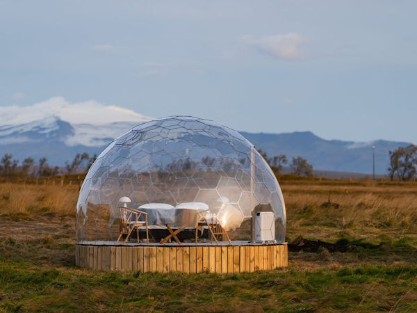 A glamping pod at Aurora Igloo, with a mountain range in the background.