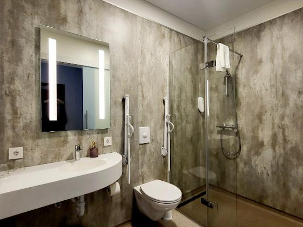 Experience chic comfort in the modern bathroom of Hotel Flokalundur, featuring stylish accents and thoughtful amenities.