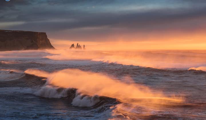 Waves roll into Reynisfjara beach at sunset.