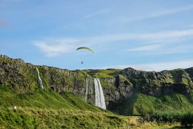 A paraglider soars above the Seljalandsfoss waterfall in South Iceland.
