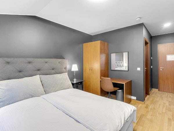 A comfortable and sophisticated room at Deluxe Lodge with a bed, closet, and desk.